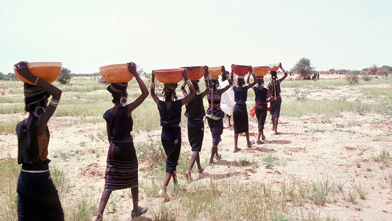A line of women in Niger carry bowls, 1978